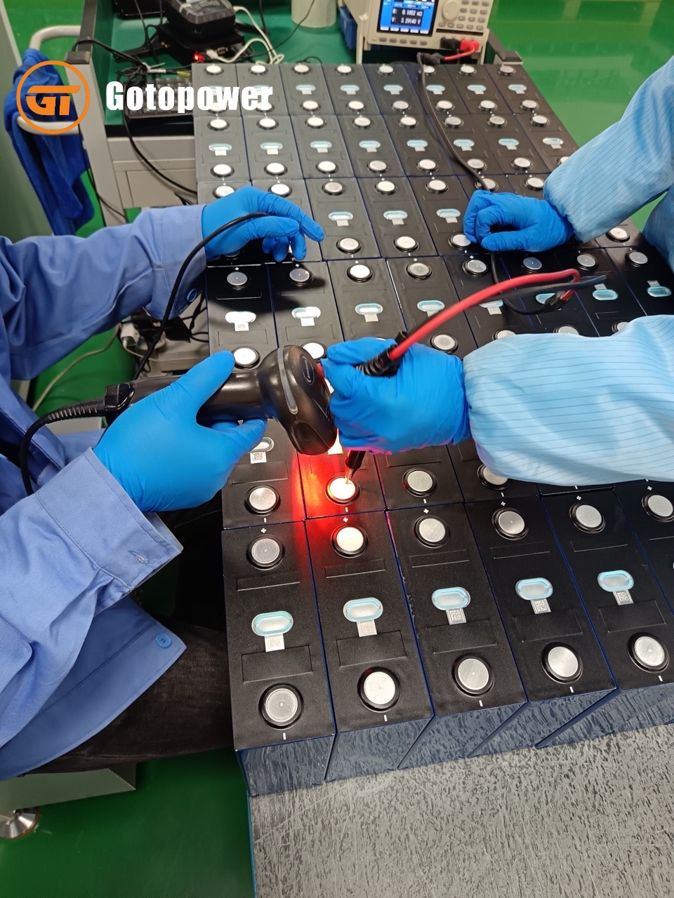 Quality control technicians scanning QR codes on prismatic LiFePO4 cells for digital traceability.